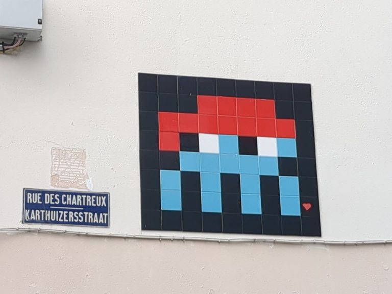 Photograph of Rue des Chartreux in Brussels with pixel art of a Space Invaders character in ceramic tiles.